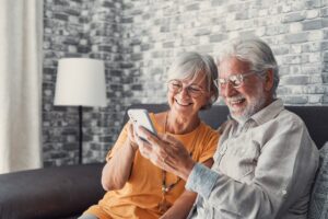 Elderly grandfather and grandmother spend time having fun using smartphone apps